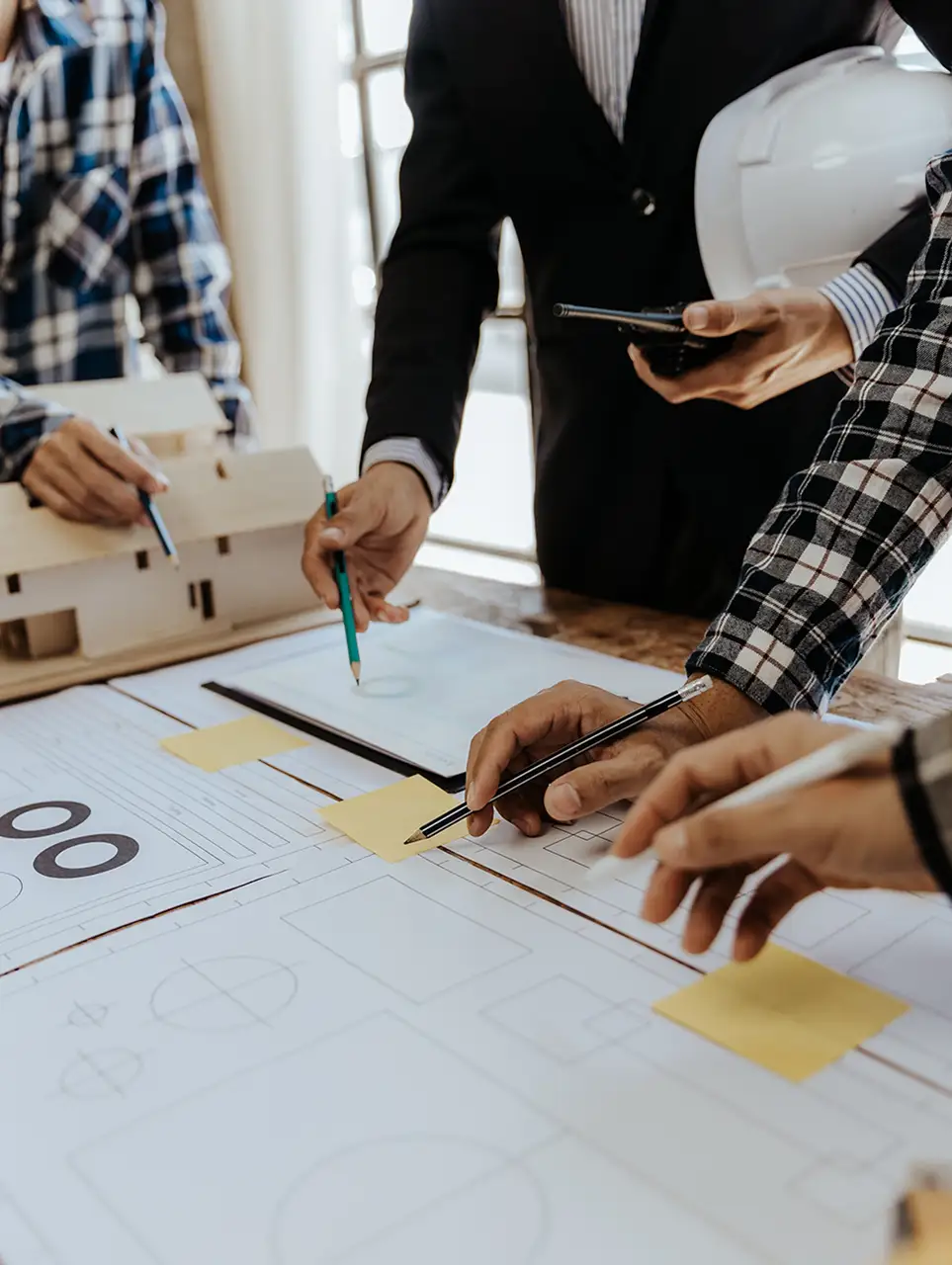 people holding pens collaborating on a construction diagram